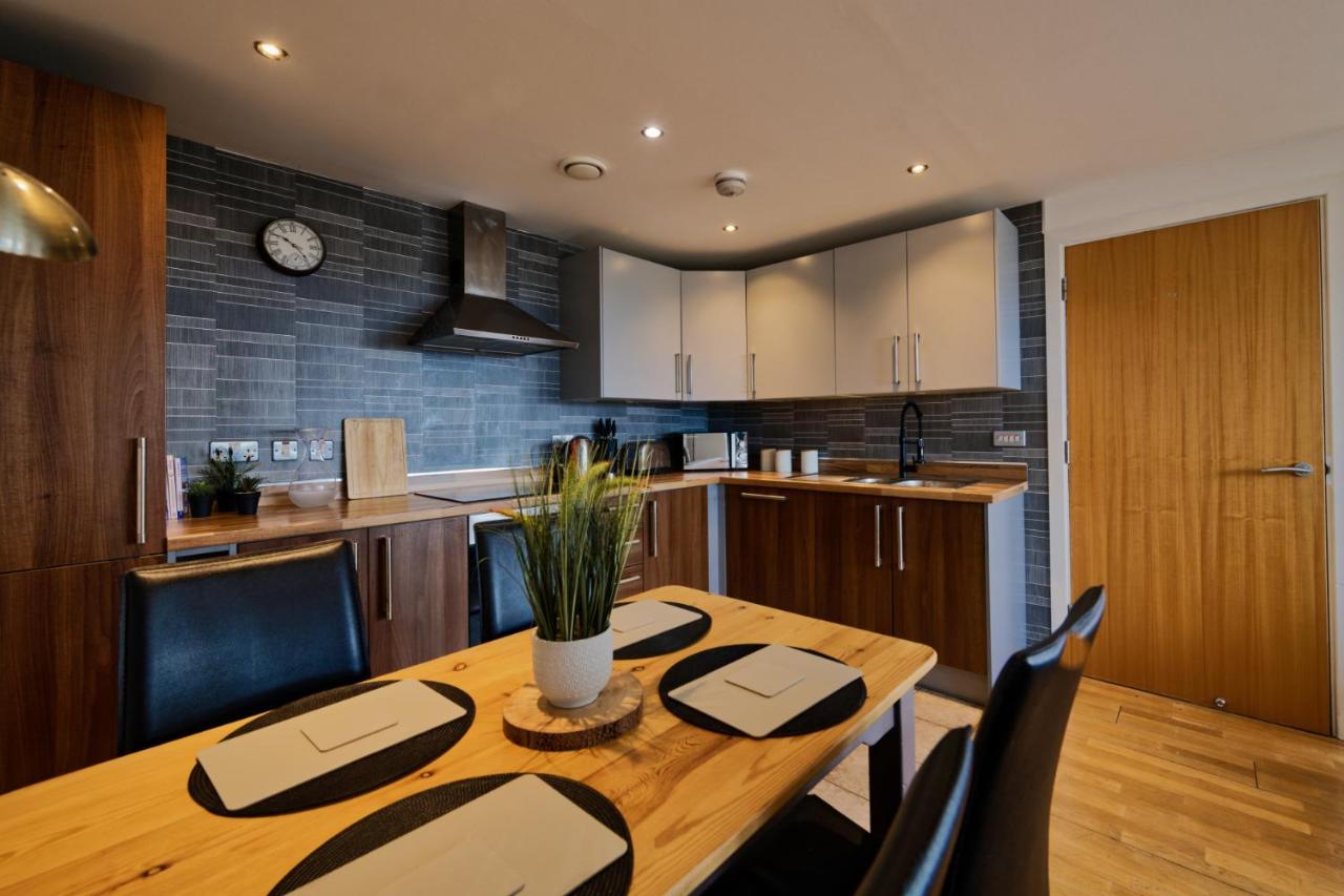 Fully equipped kitchen with wooden dining table in the accessible two-bedroom Liverpool apartment